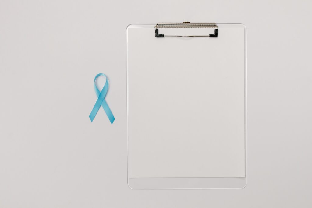 Cancer screening awareness ribbon beside a medical clipboard